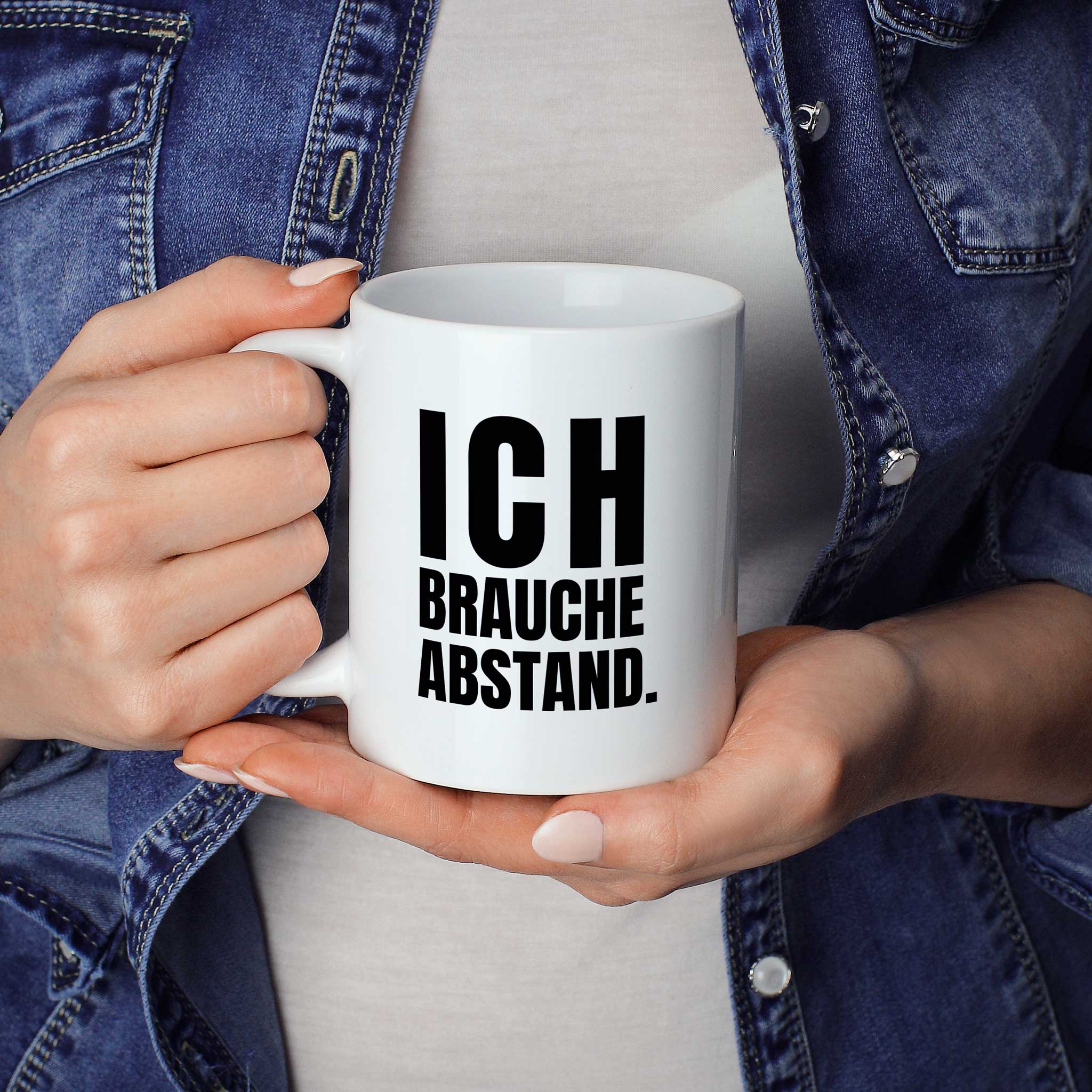 Brüllerware Statement-Tasse „Ich brauche Abstand.“ in der Hand gehalten – beidseitig bedruckte Kaffeetasse