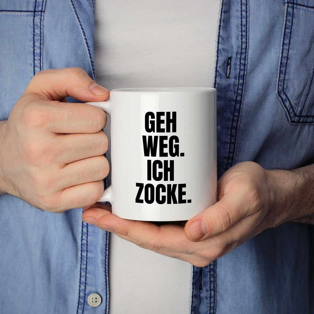 Brüllerware Statement-Tasse „Geh weg. Ich zocke.“ in der Hand gehalten – beidseitig bedruckte Kaffeetasse