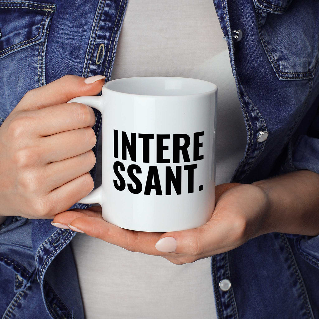 Brüllerware Statement-Tasse „Interessant“ in der Hand gehalten – beidseitig bedruckte Kaffeetasse
