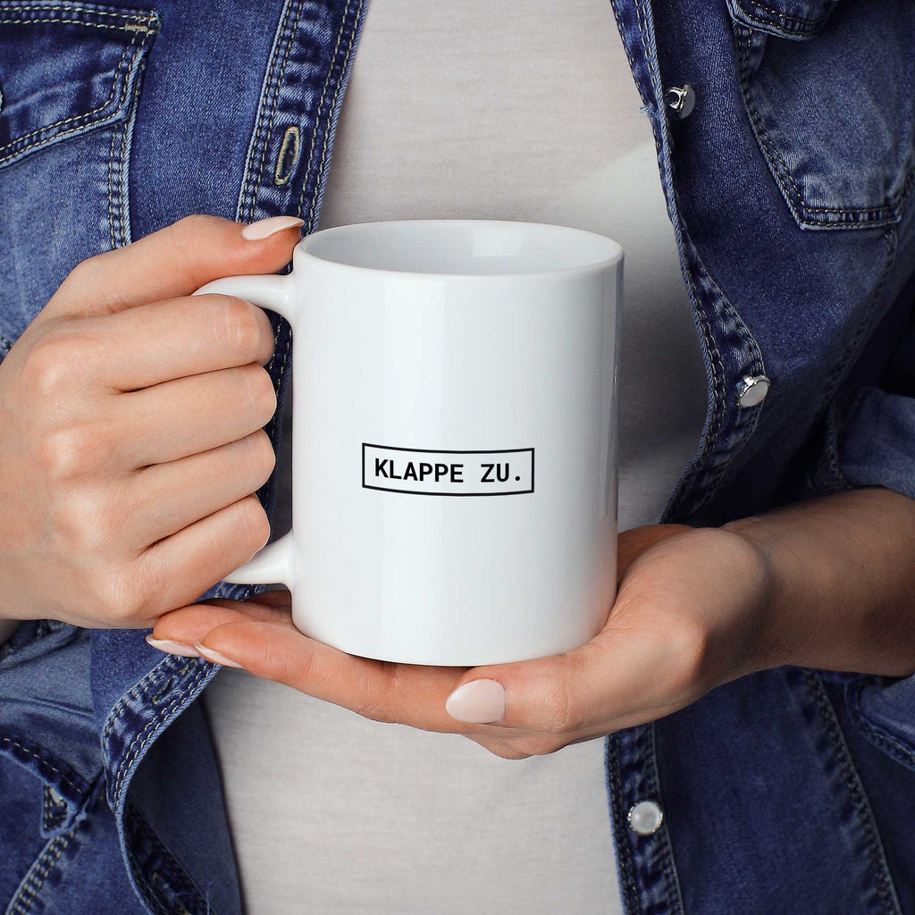 Brüllerware Statement-Tasse „Klappe zu.“ in der Hand gehalten – beidseitig bedruckte Kaffeetasse