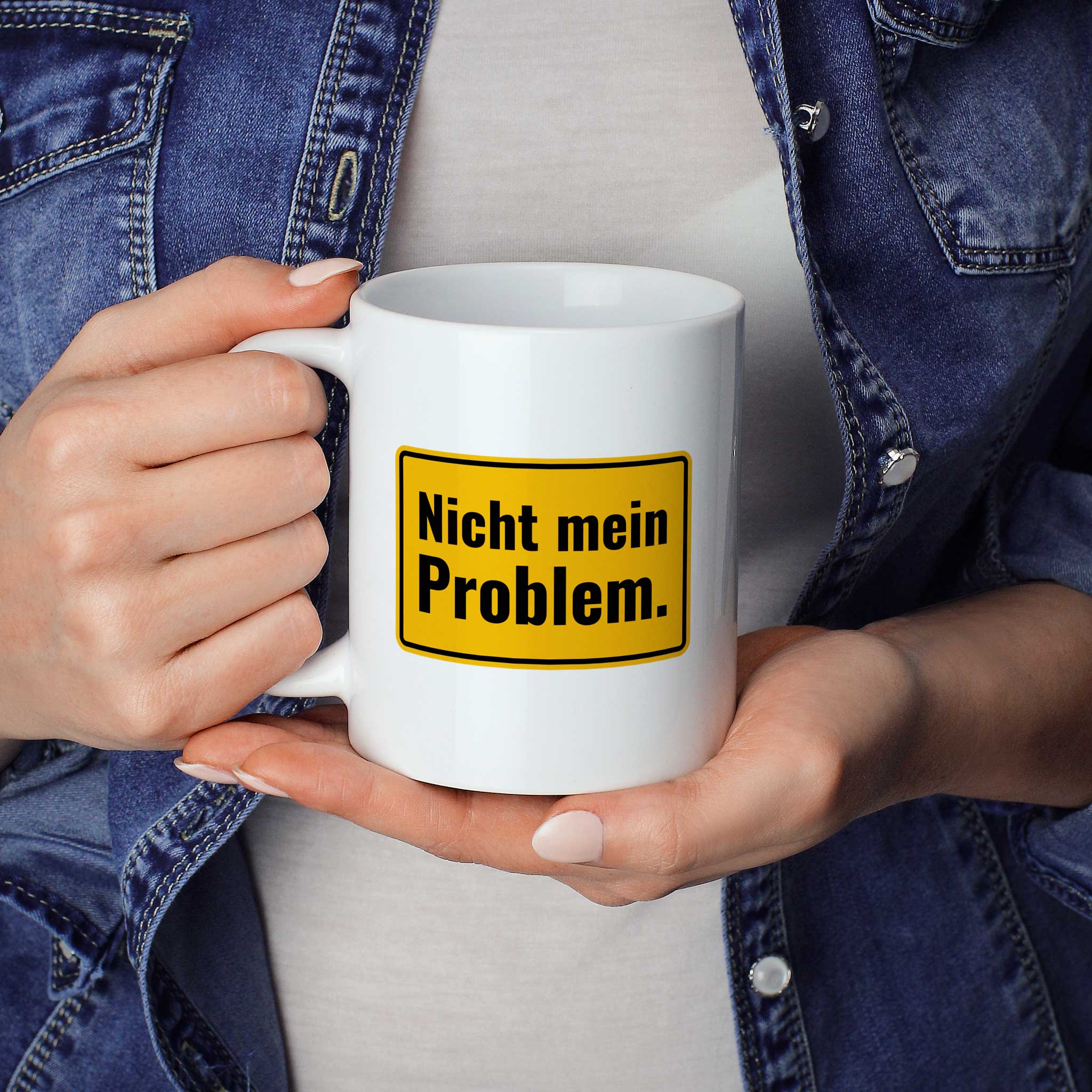 Brüllerware Statement-Tasse „Nicht mein Problem.“ in der Hand gehalten – beidseitig bedruckte Kaffeetasse