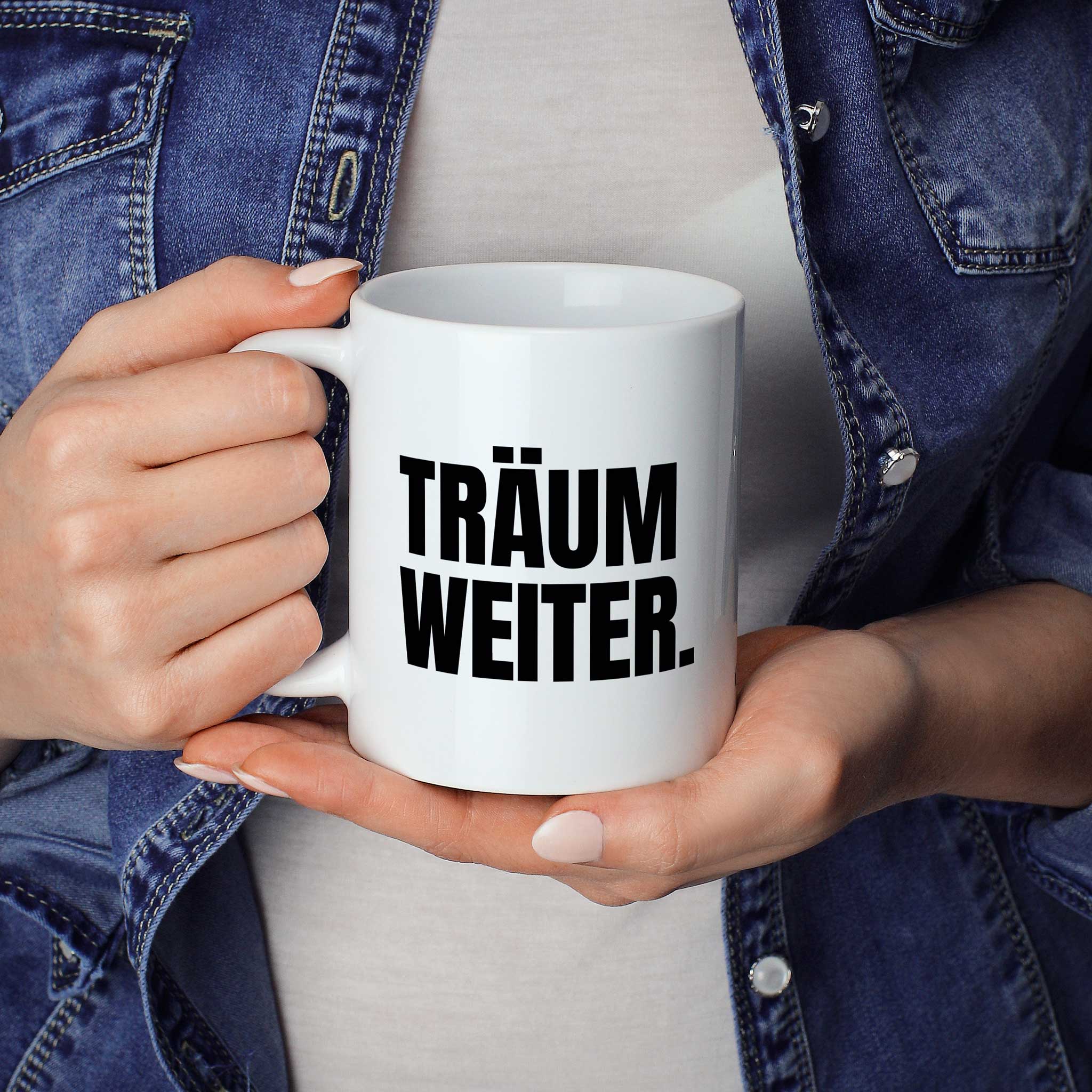 Brüllerware Statement-Tasse „Träum weiter.“ in der Hand gehalten – beidseitig bedruckte Kaffeetasse