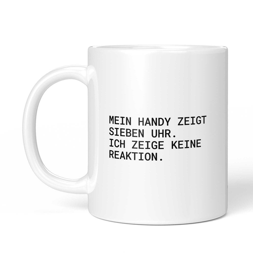 Weiße Tasse „Mein Handy zeigt sieben Uhr“ mit Henkel links