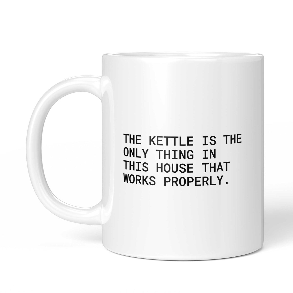Weiße Tasse „The kettle is the only thing that works properly“ mit Henkel links