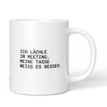 Weiße Keramiktasse mit dem Spruch „Ich lächle im Meeting. Meine Tasse weiß es besser.“ von Brüllerware
