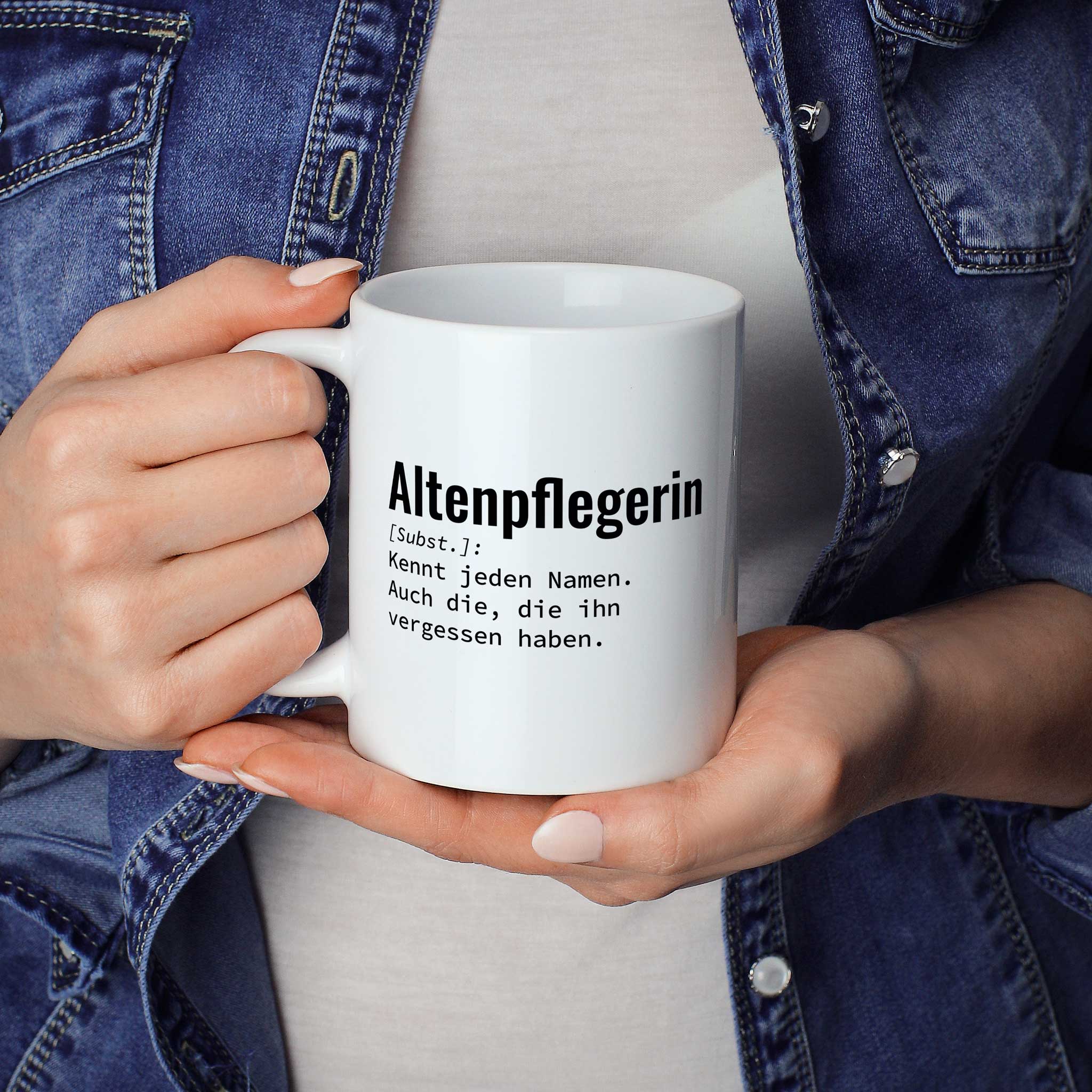 Frau hält lustige Tasse mit Spruch „Altenpflegerin: Kennt jeden Namen. Auch die, die ihn vergessen haben." in beiden Händen – Größenvergleich, 330 ml Keramiktasse