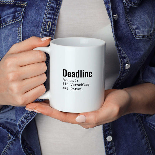 Frau hält lustige Tasse mit Spruch „Deadline: Ein Vorschlag mit Datum." in beiden Händen – Größenvergleich, 330 ml Keramiktasse