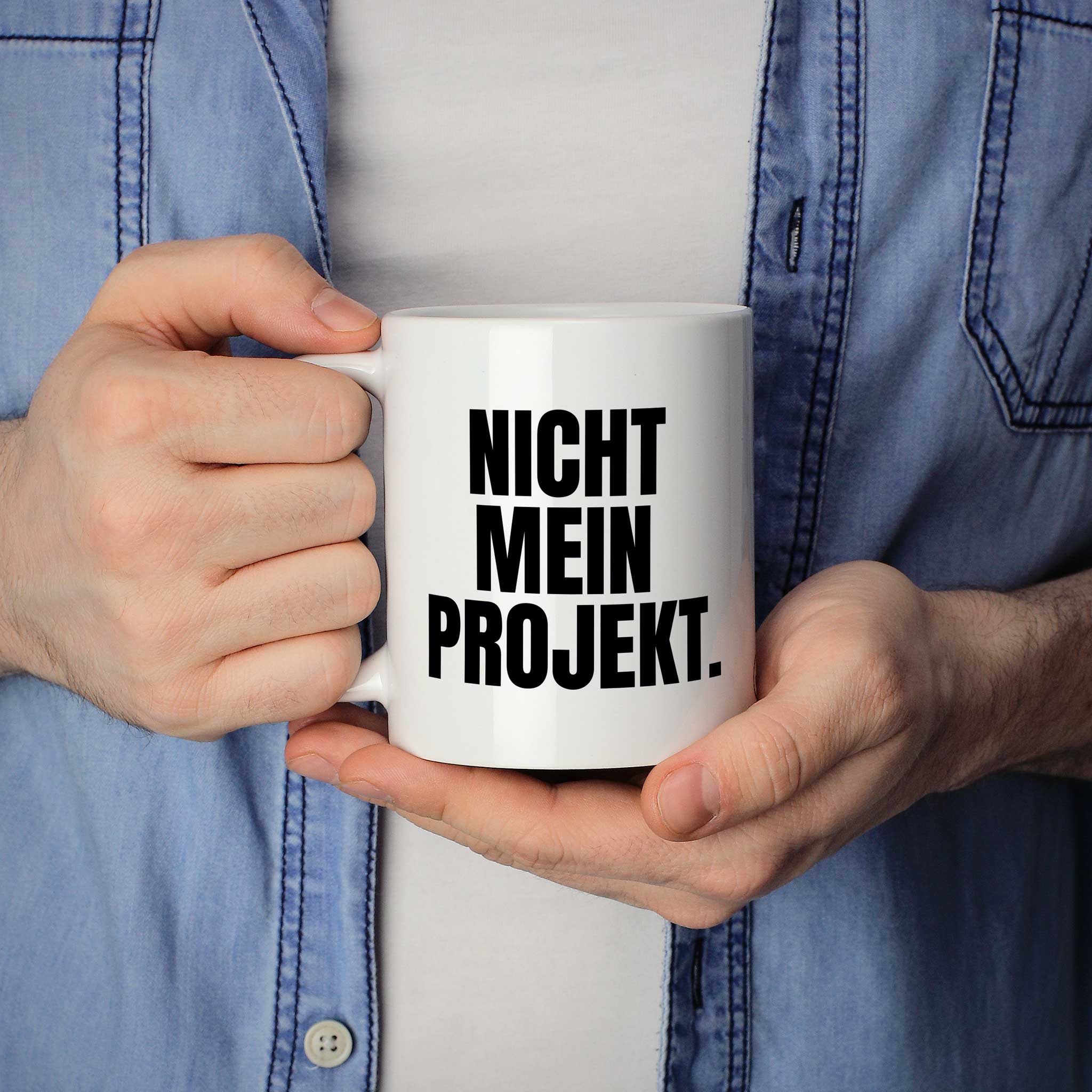 Mann hält lustige Tasse mit Spruch „Nicht mein Projekt." in beiden Händen – Größenvergleich, 330 ml Keramiktasse