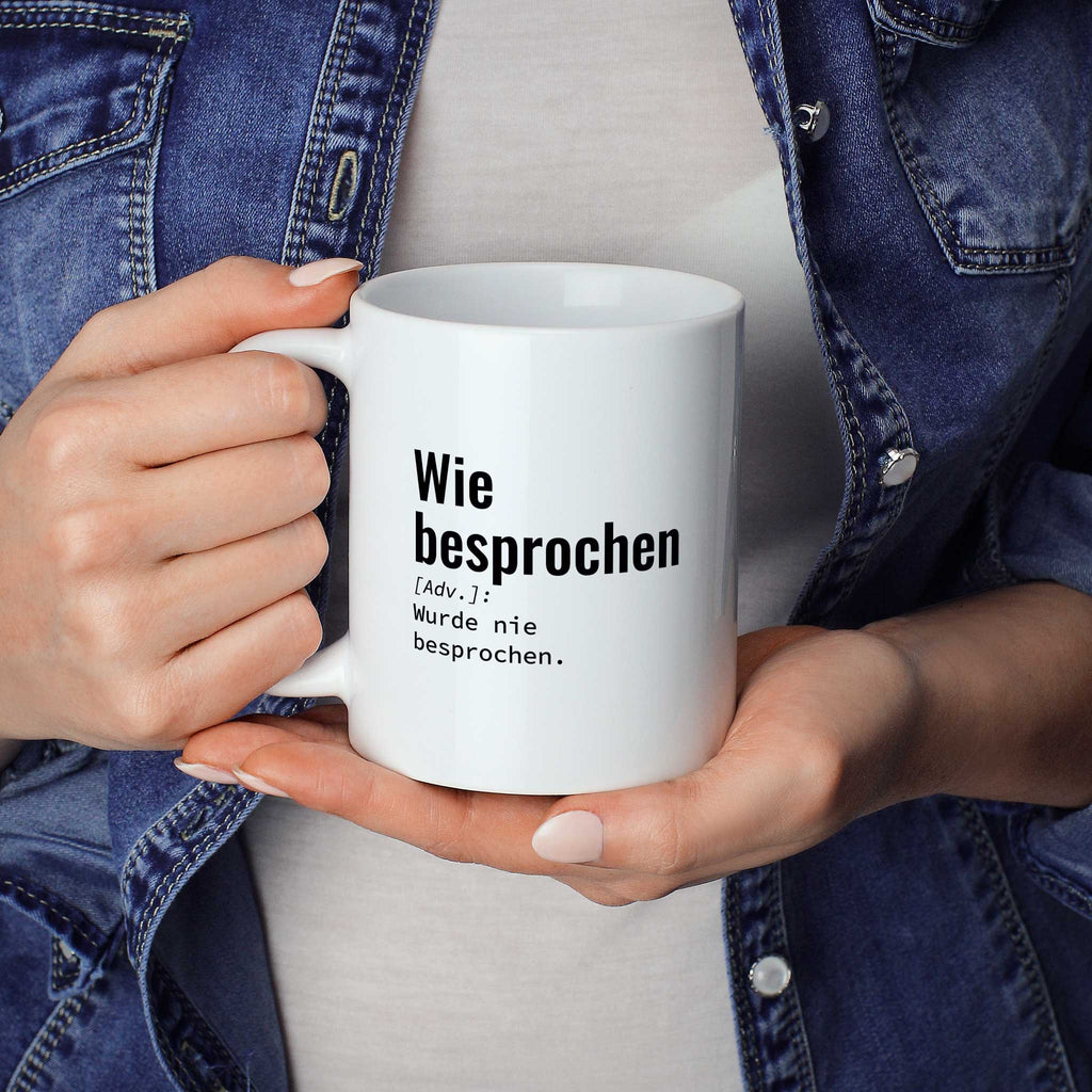 Frau hält lustige Tasse mit Spruch „Wie besprochen: Wurde nie besprochen." in beiden Händen – Größenvergleich, 330 ml Keramiktasse