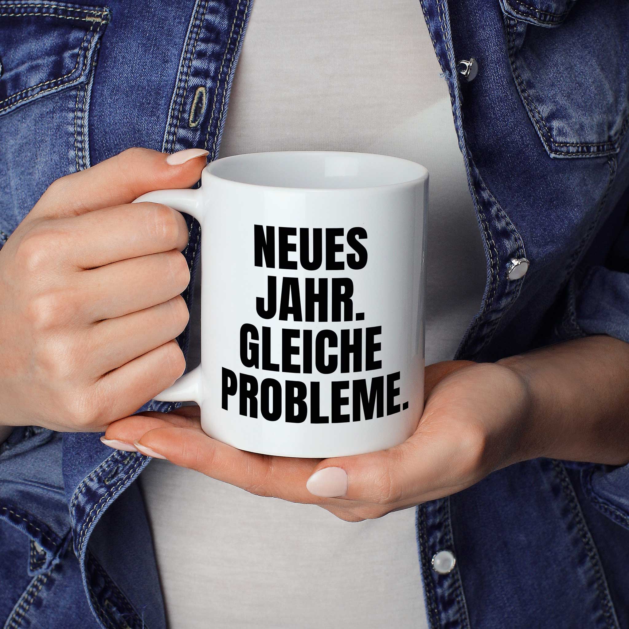 Brüllerware Statement-Tasse „Neues Jahr. Gleiche Probleme.“ in der Hand gehalten – beidseitig bedruckte Kaffeetasse