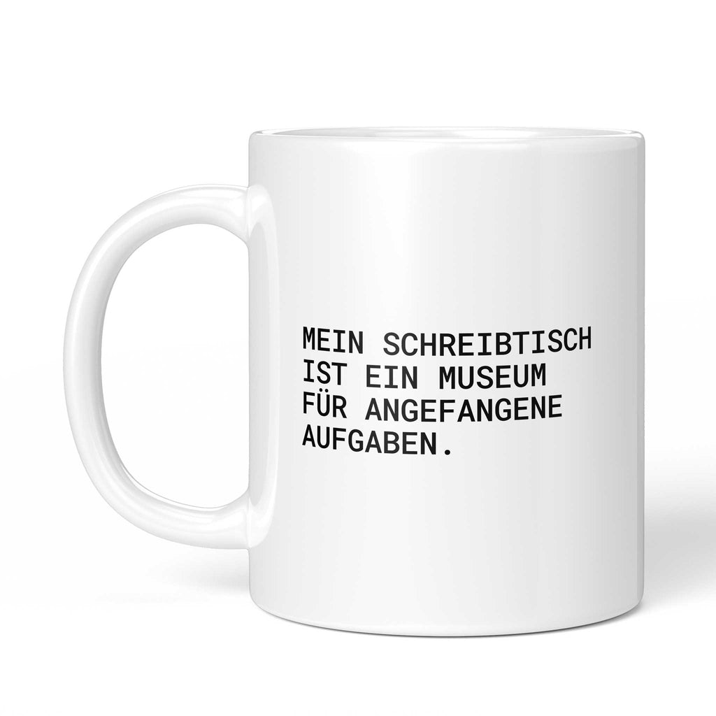 Weiße Tasse „Mein Schreibtisch ist ein Museum“ mit Henkel links
