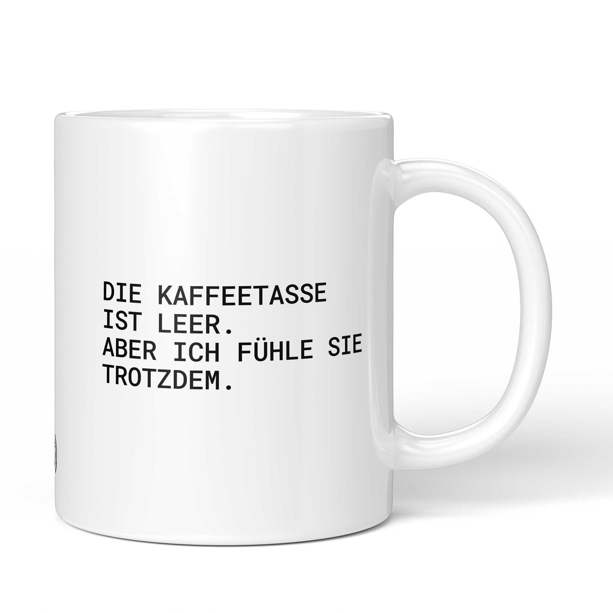 Weiße Tasse mit Spruch „Die Kaffeetasse ist leer – aber ich fühle sie trotzdem.“ – Brüllerware