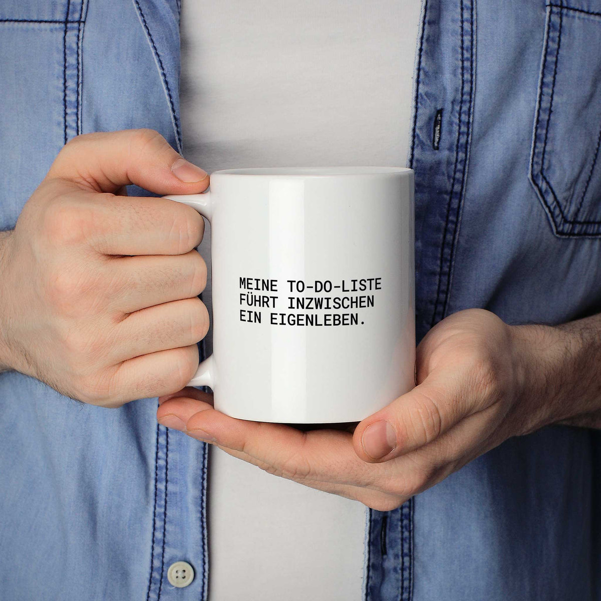 Weiße Tasse „Meine To-do-Liste führt inzwischen ein Eigenleben.“ in beiden Händen gehalten