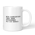 Weiße Tasse mit Spruch „Mein Schreibtisch trägt mehr Aktenordner als ich Geduld.“ – Brüllerware