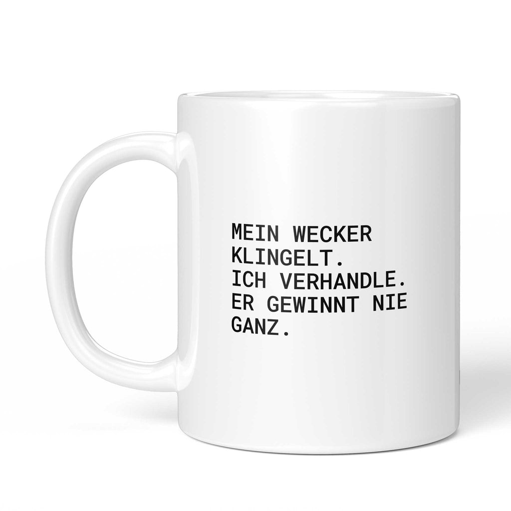 Tasse „Mein Wecker klingelt. Ich verhandle. Er gewinnt nie ganz.“ – Ansicht mit Henkel links
