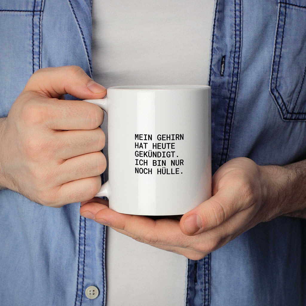 Weiße Tasse „Mein Gehirn hat heute gekündigt – ich bin nur noch Hülle.“ in beiden Händen gehalten