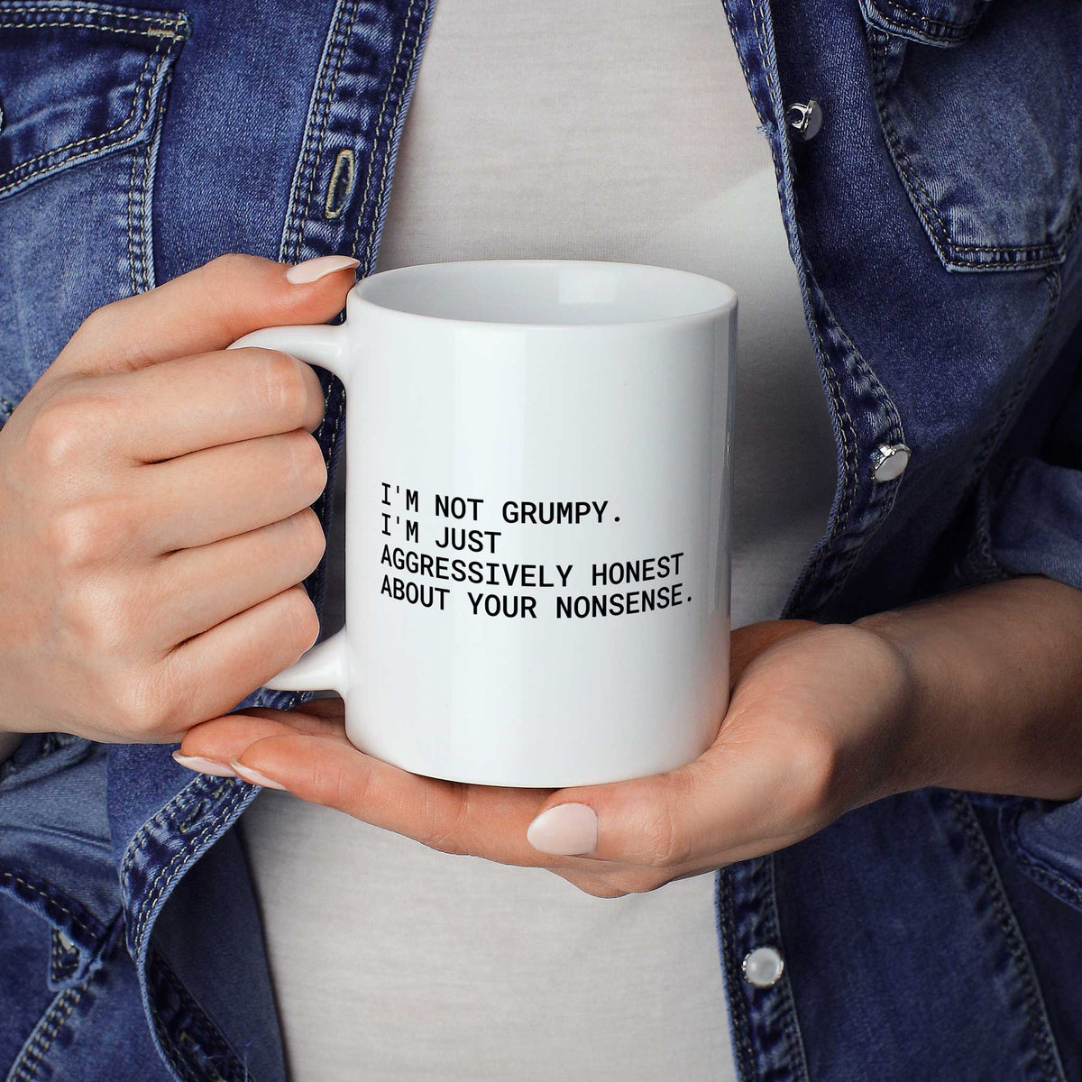 Weiße Tasse „I'm not grumpy. I'm just aggressively honest about your nonsense.“ in beiden Händen gehalten
