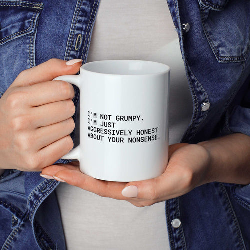 Weiße Tasse „I'm not grumpy. I'm just aggressively honest about your nonsense.“ in beiden Händen gehalten