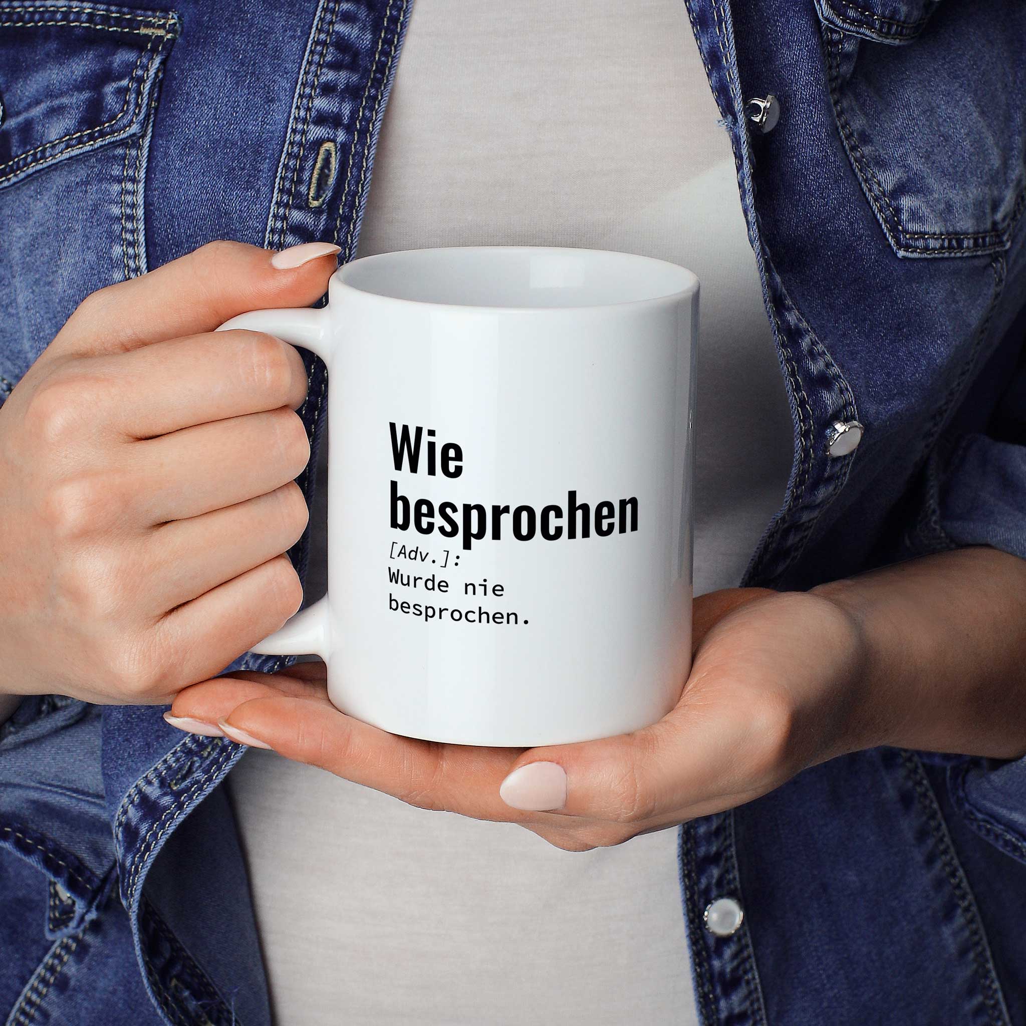 Person hält Tasse mit Spruch „Wie besprochen [Adv.]: Wurde nie besprochen.“ in beiden Händen