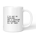 Weiße Keramiktasse mit dem Spruch „I’ve got 99 problems – and a caffeine deficiency is all of them.“ von Brüllerware