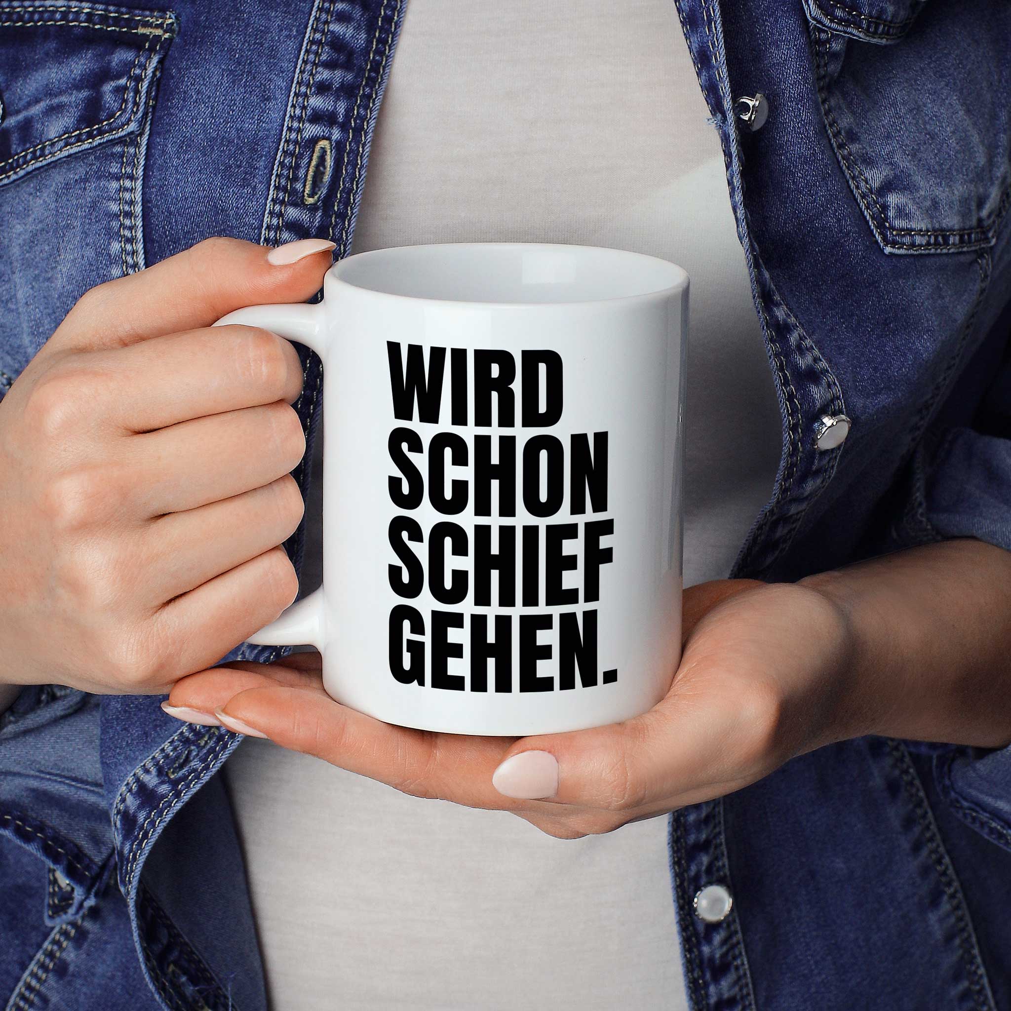 Brüllerware Statement-Tasse „Wird schon schief“ in der Hand gehalten – beidseitig bedruckte Kaffeetasseehen.