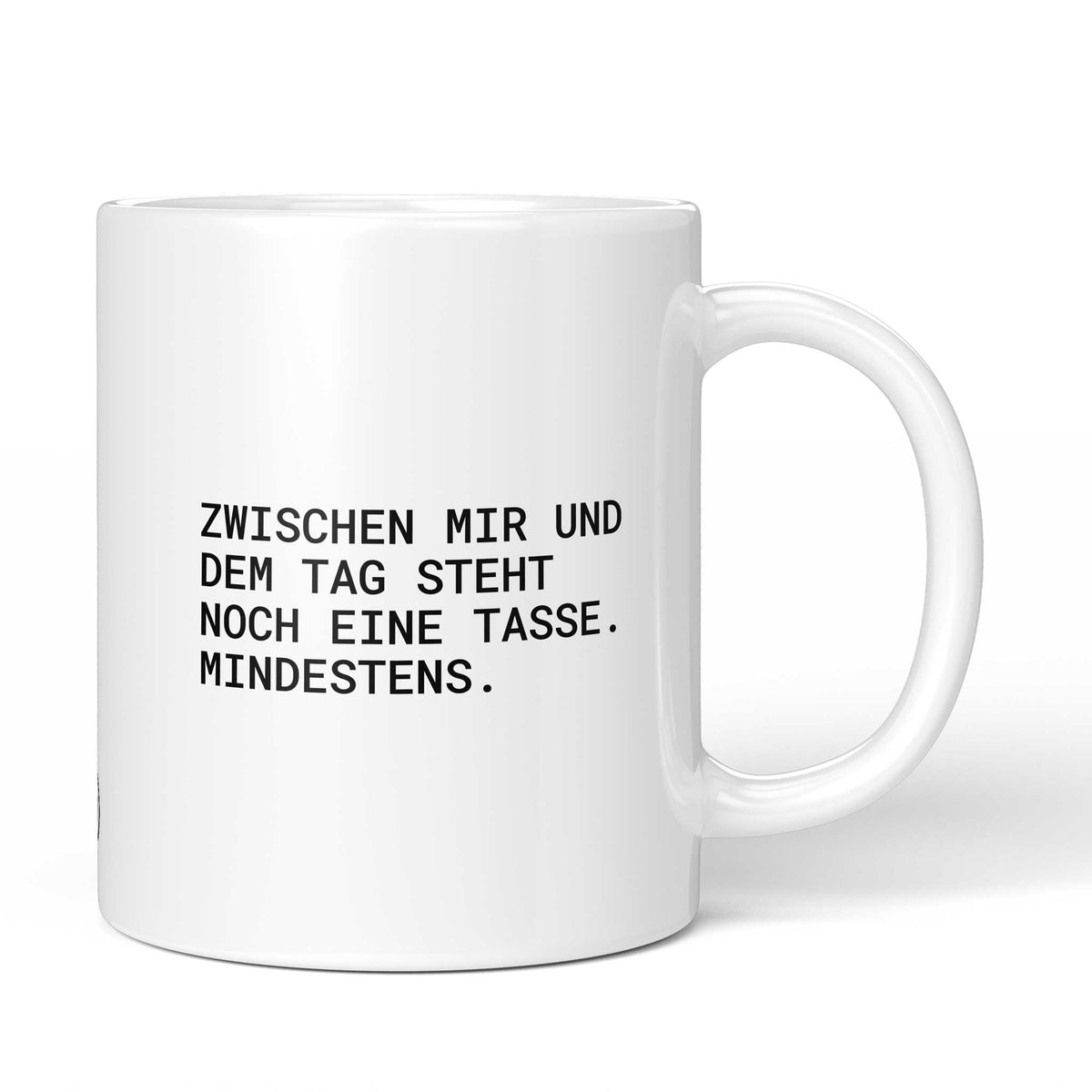 Weiße Keramiktasse mit dem Spruch „Zwischen mir und dem Tag steht noch eine Tasse. Mindestens.“ von Brüllerware